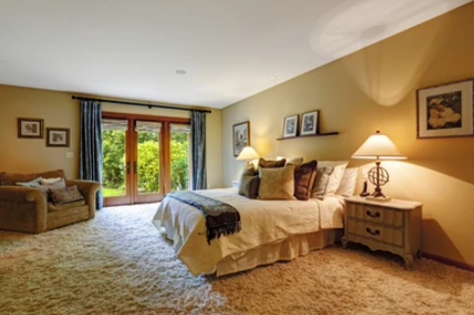 Cozy bedroom with warm lighting, soft carpet, and inviting decor creating a comfortable home atmosphere.