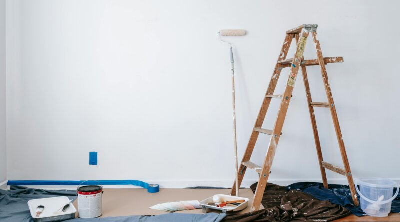 A homeowner comparing home improvement vs construction with renovation tools and a house blueprint.
