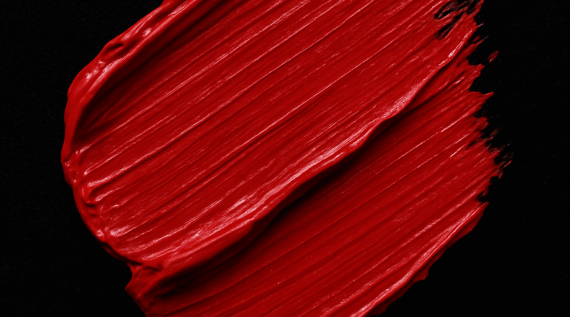Close-up of red velvet paint texture with a smooth, satin-like finish on a dark background.